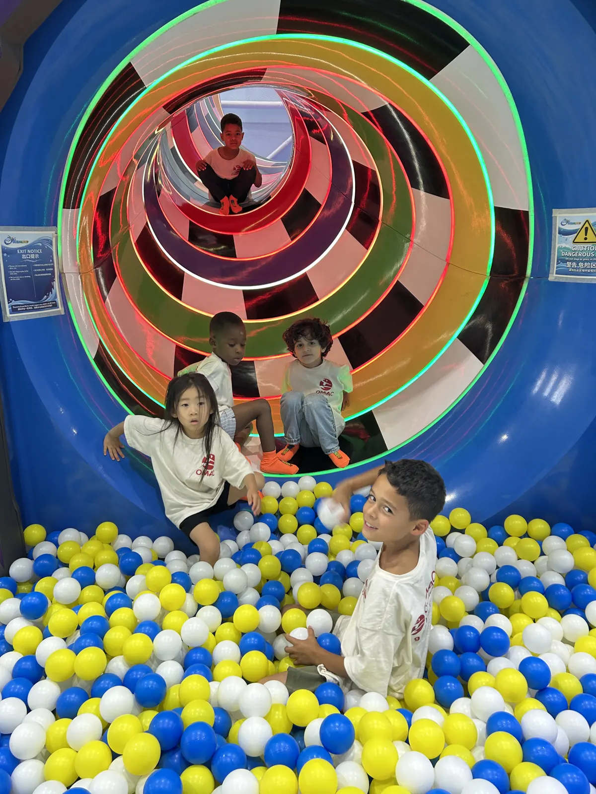 Kids in OMAC camp shirts playing in a ball pit