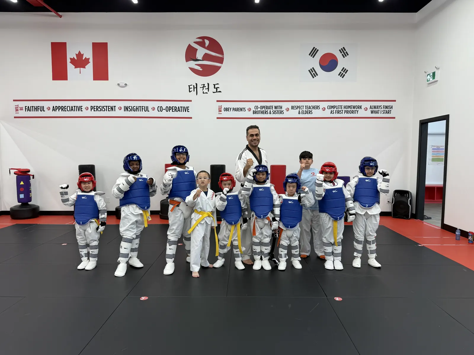 A group of students in sparring gear with their instructors